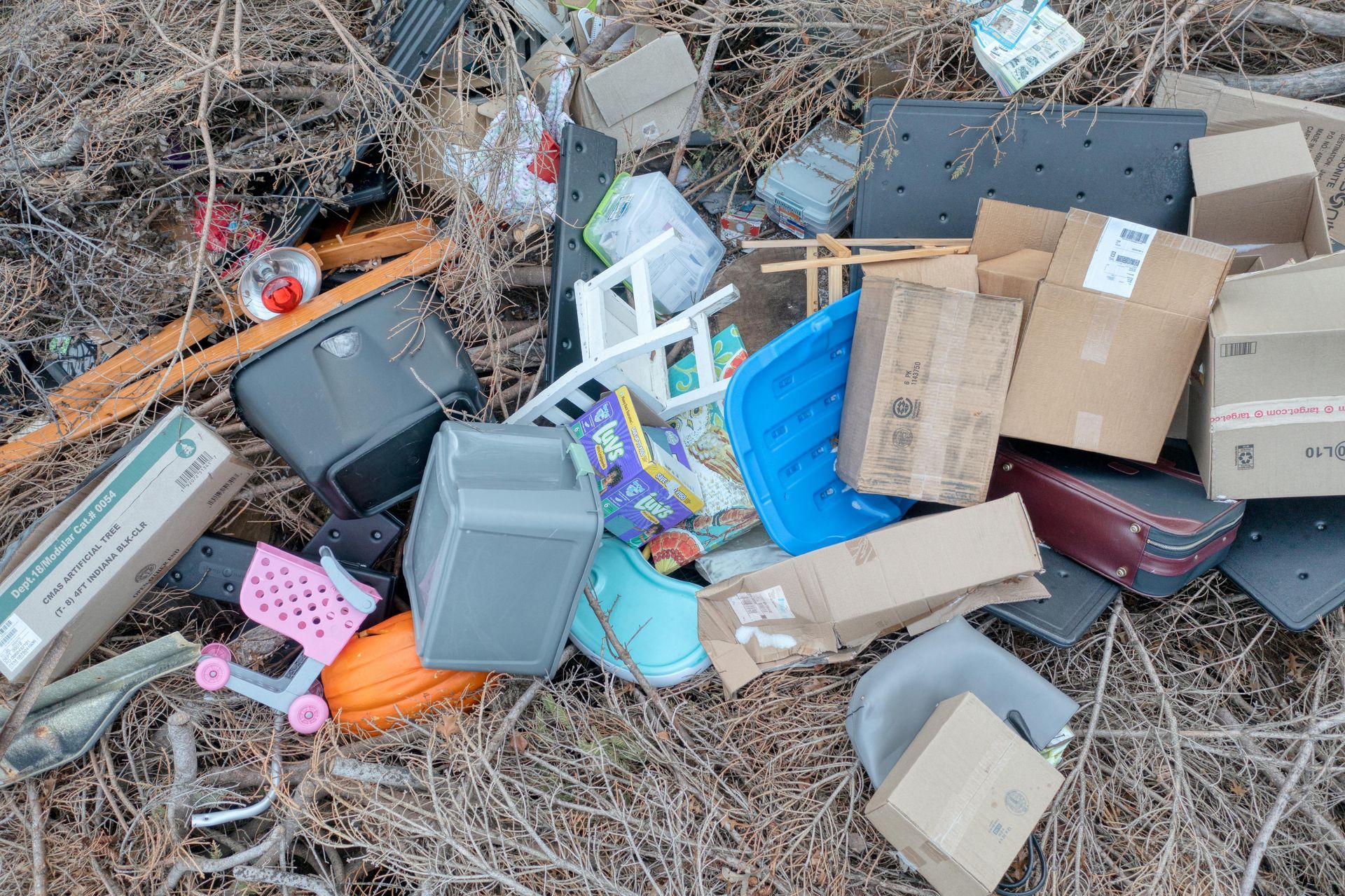 Pile of mixed trash and cardboard boxes scattered on dry ground outdoors