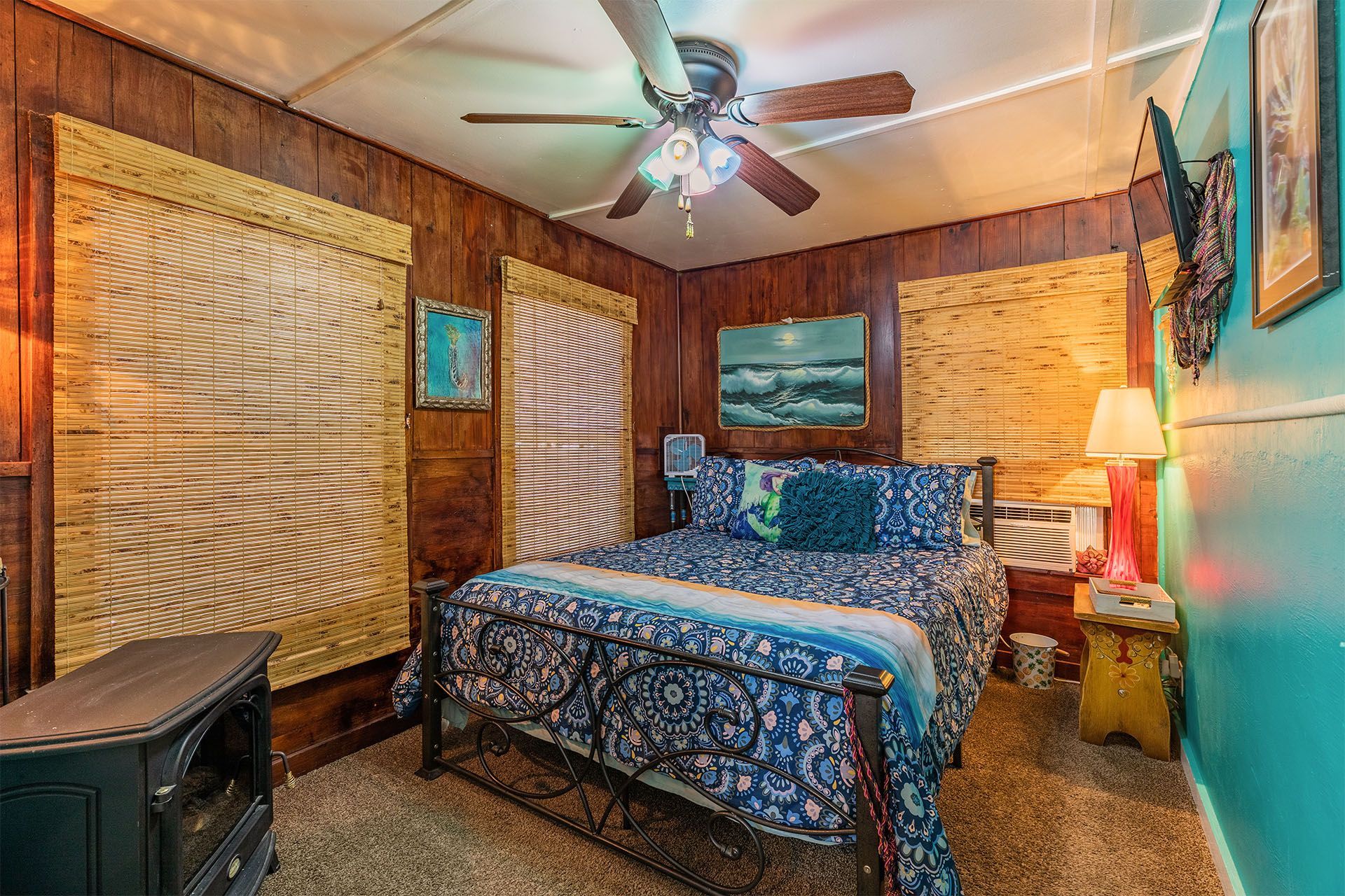 Bedroom with brown paneling, blue bedding, and a decorative ceiling fan.