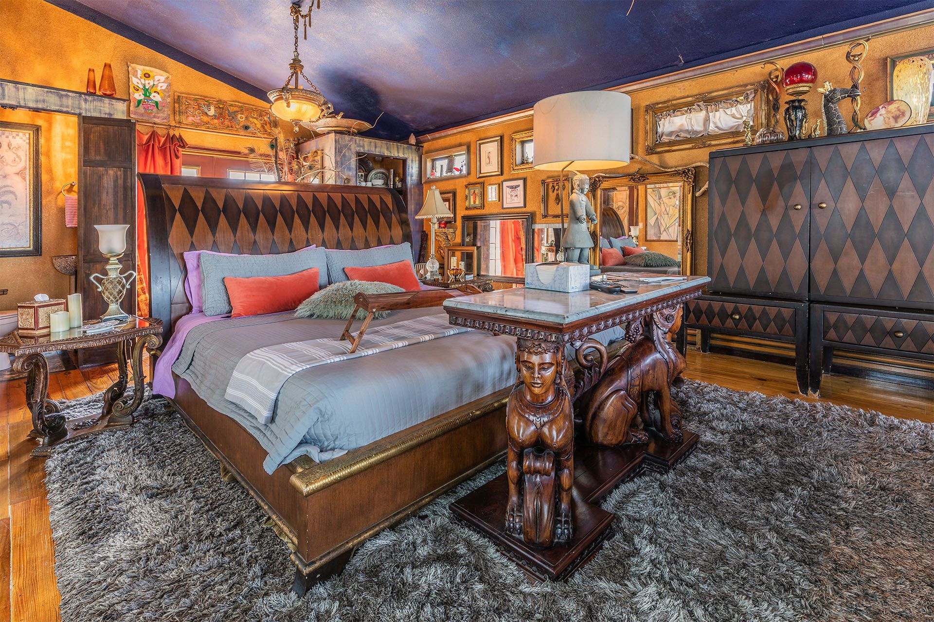 Opulent bedroom with dark wood bed, ornate furniture, and colorful decor.