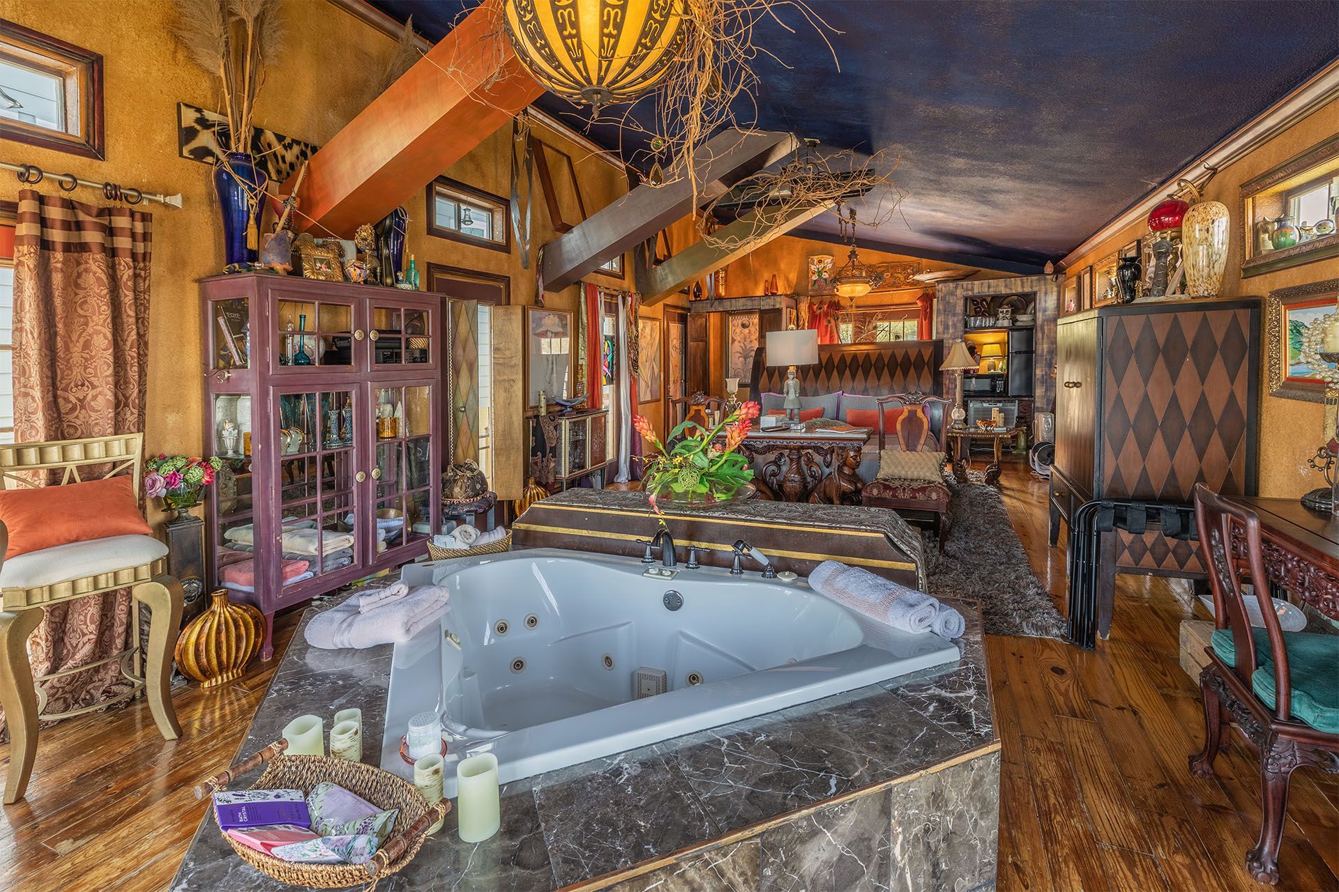 Luxurious interior with jacuzzi, ornate furniture, and eclectic decor; blue ceiling, gold walls.