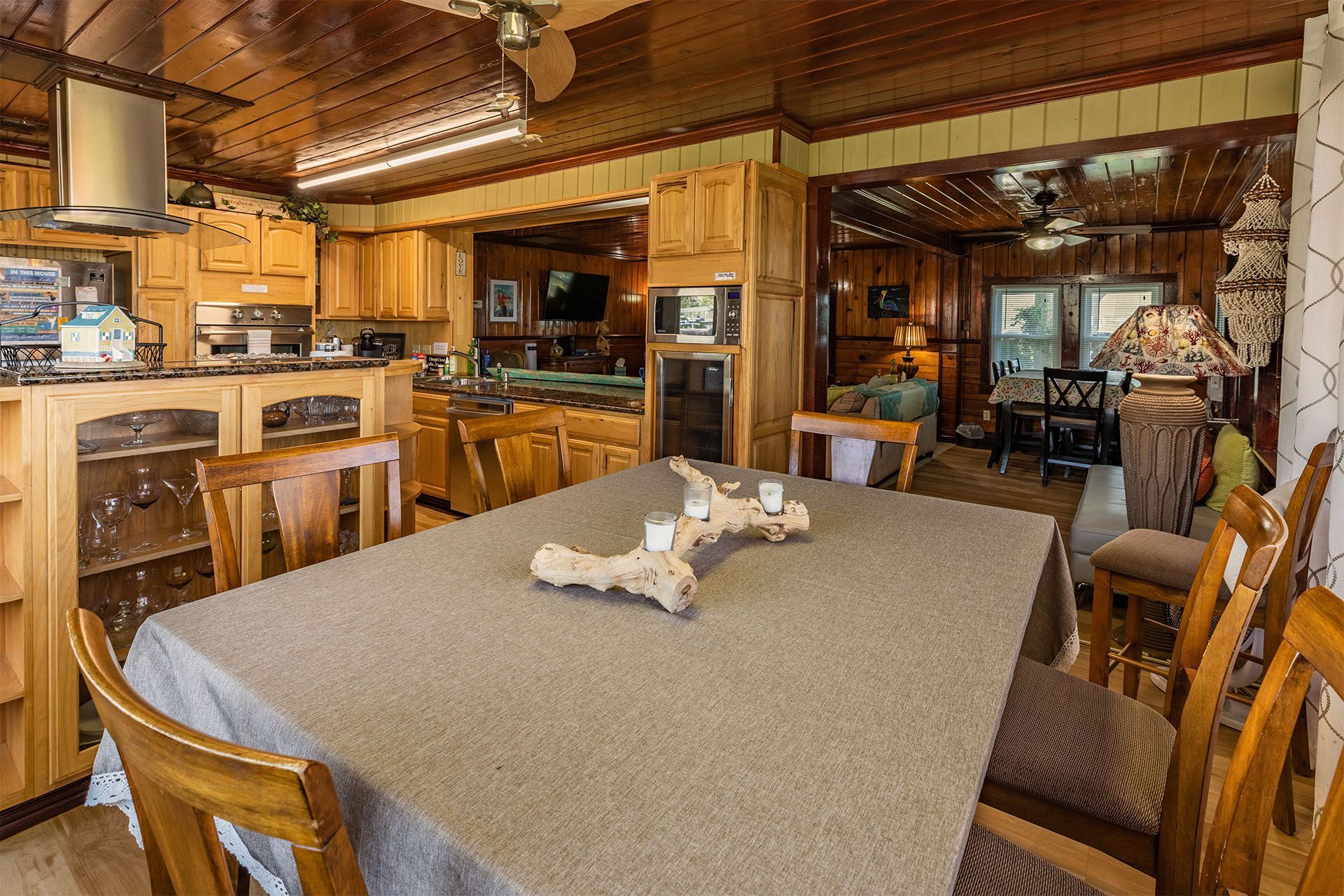 Dining room with wood table, chairs, and a kitchen visible in the background.