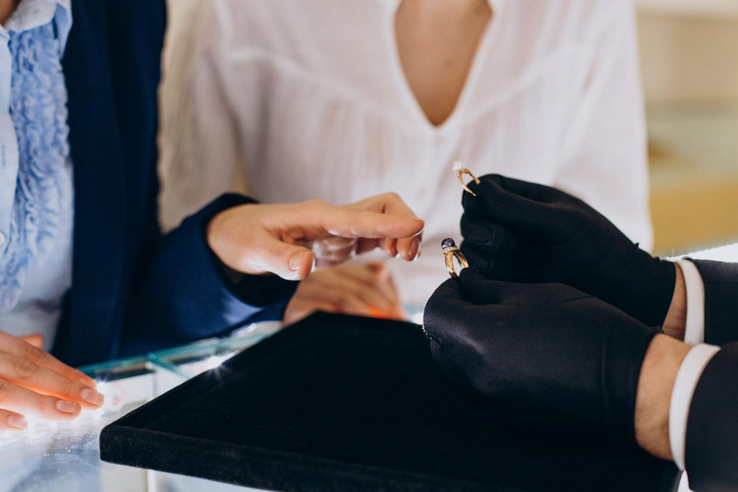 A woman is getting her nails done by a man in black gloves.
