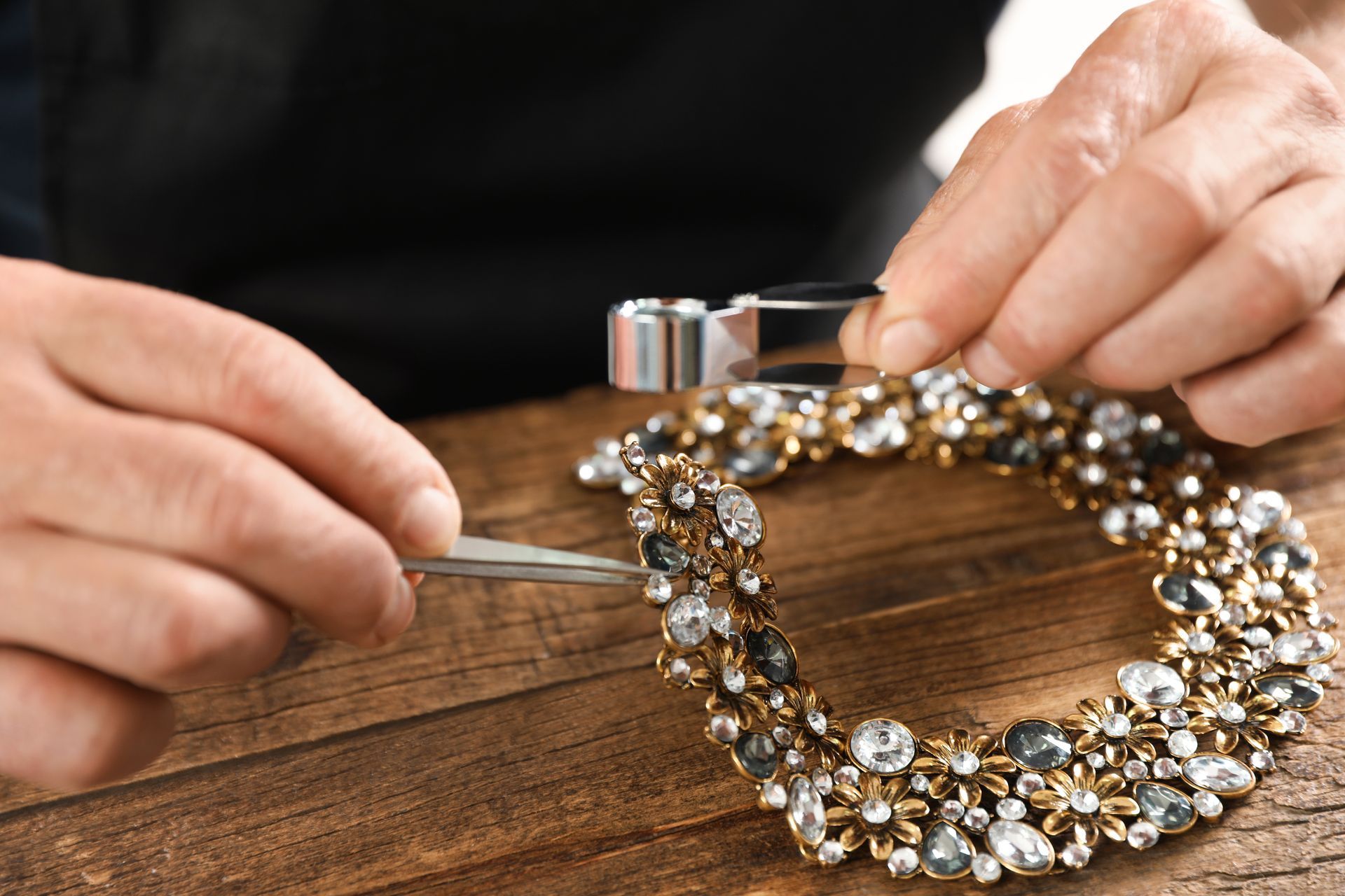 A person is working on a bracelet with a magnifying glass.