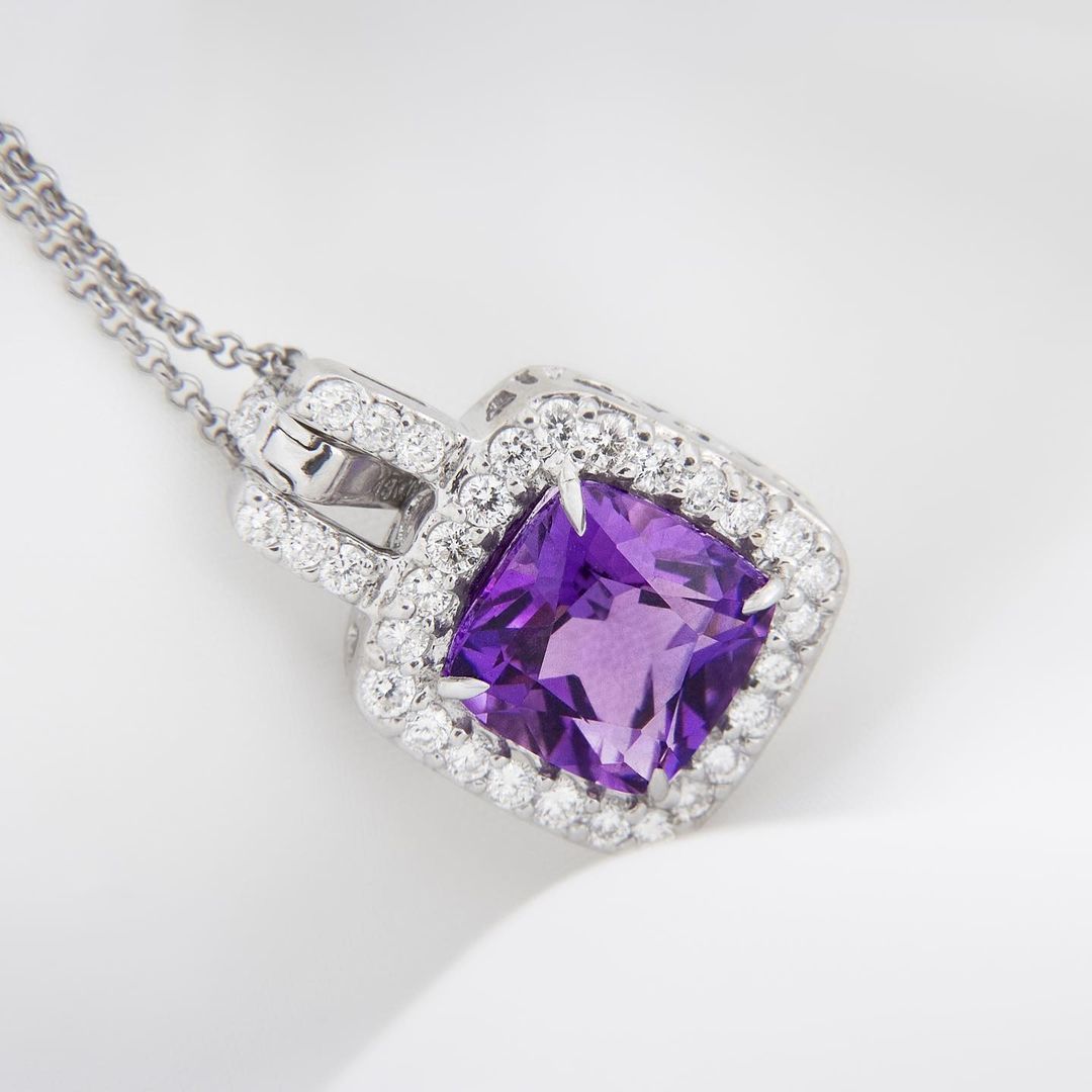 Silver necklace with a square purple gemstone pendant surrounded by white diamonds.