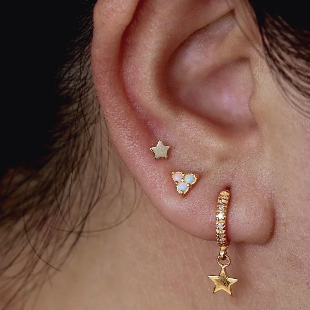 A close up of a woman 's ear with three pairs of earrings.