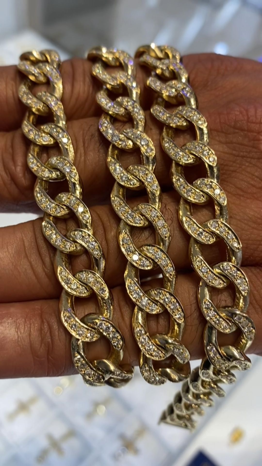A person is holding a gold chain with diamonds in their hand.