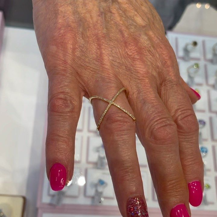 A woman 's hand with pink nails and a gold ring