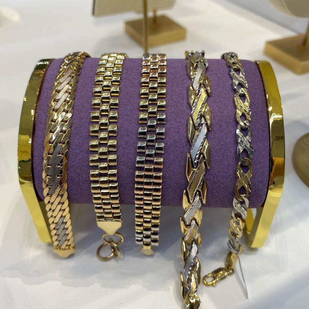 A display of gold and silver bracelets on a purple cloth