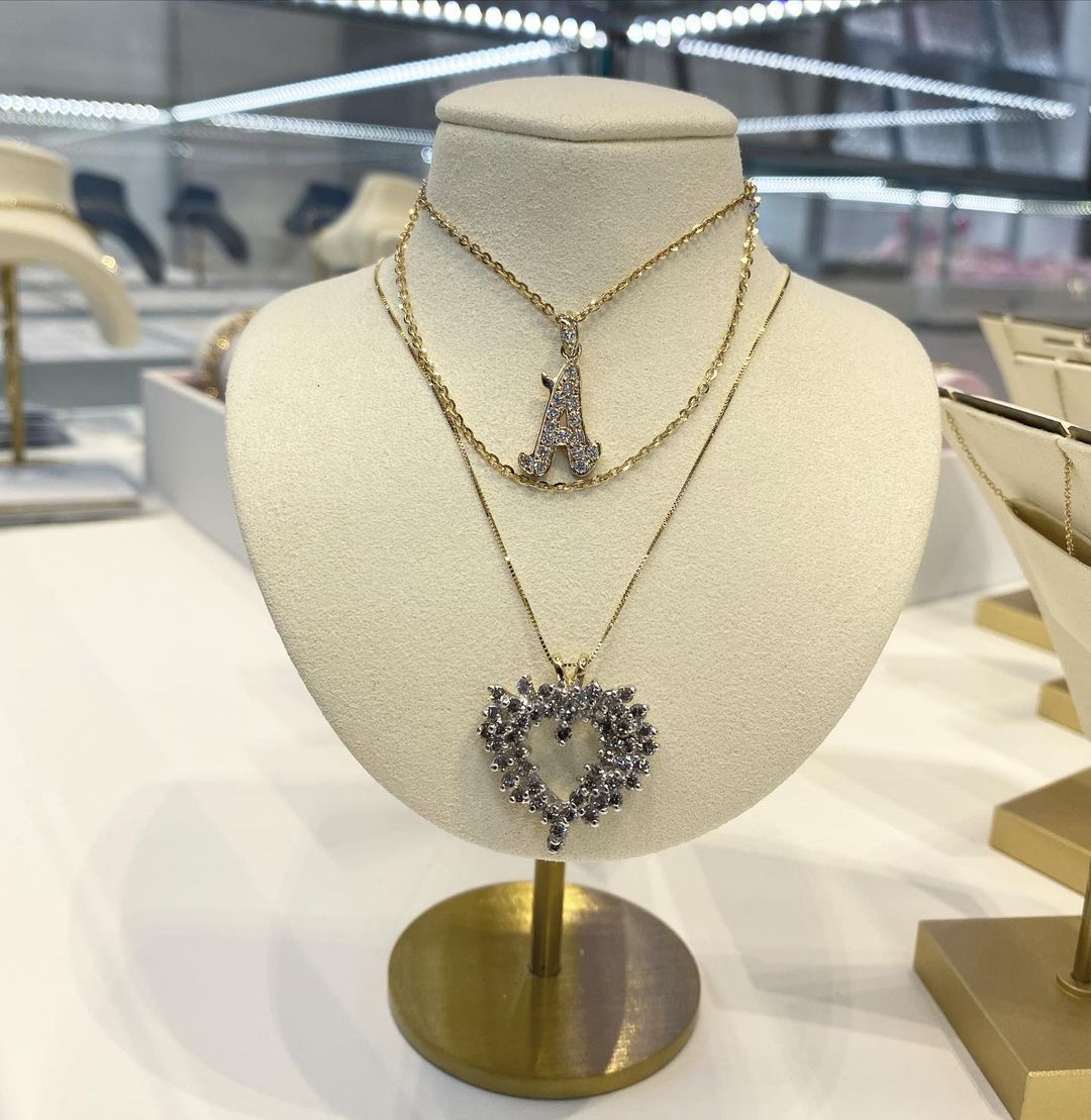 A necklace with a heart shaped pendant is on a mannequin