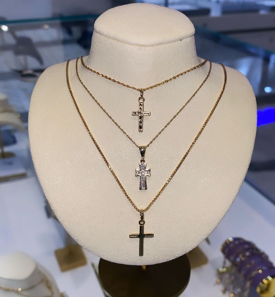 A mannequin is wearing three necklaces with crosses on them