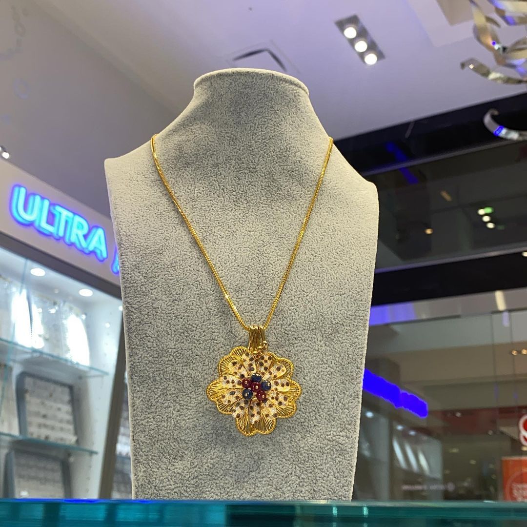 A necklace is on a mannequin in front of a sign that says ultra