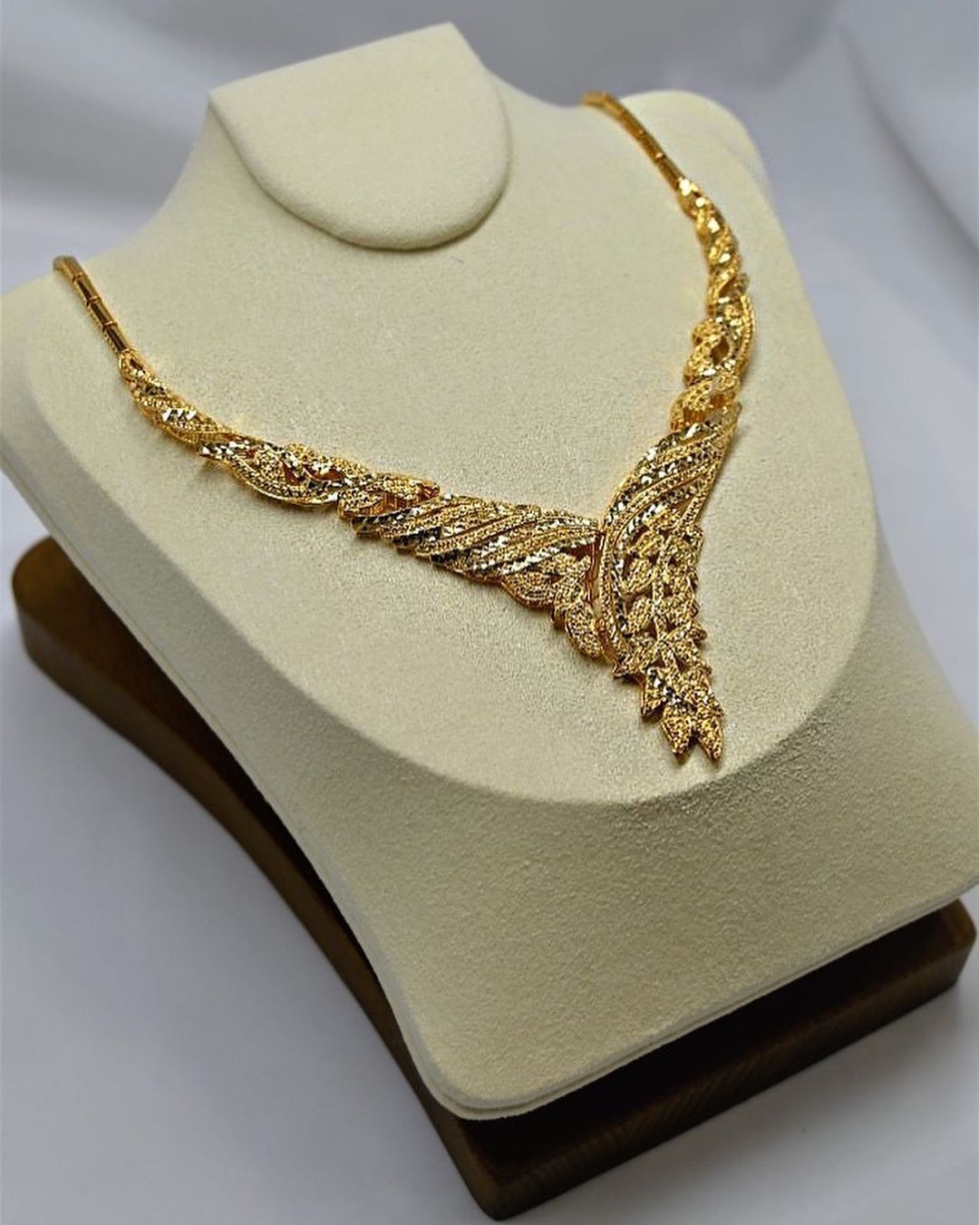 A gold necklace is displayed on a mannequin