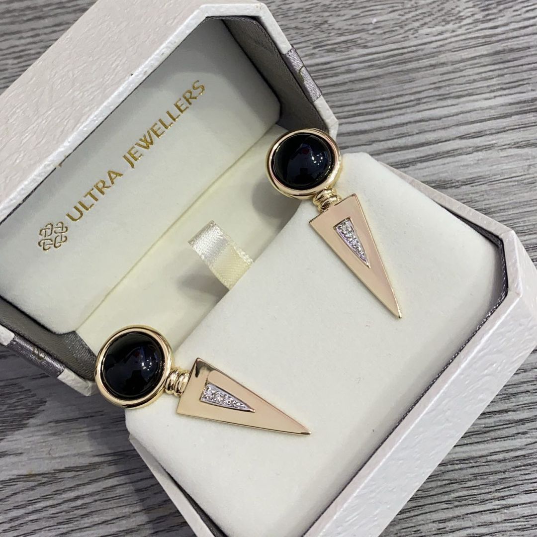 A pair of earrings in a box that says ultra jeweller 's