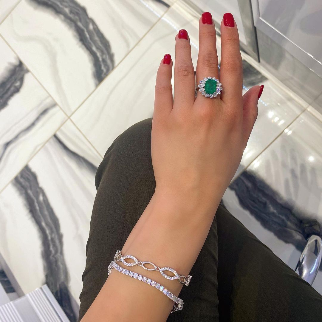 A woman with red nails is wearing a ring and bracelet