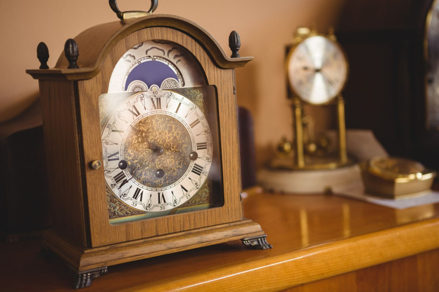 A wooden clock is sitting on a wooden table next to another clock.