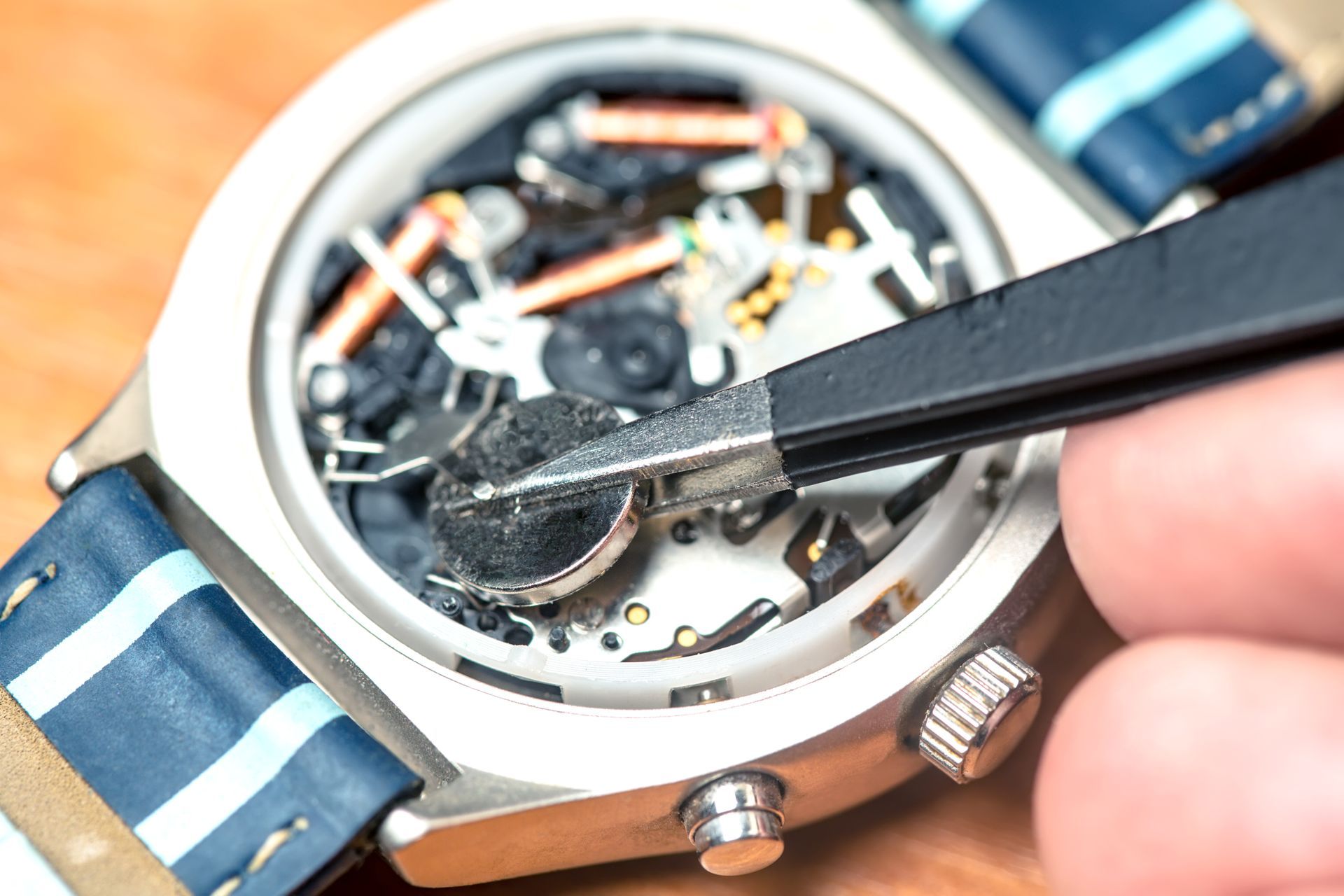 A person is fixing a watch with tweezers.