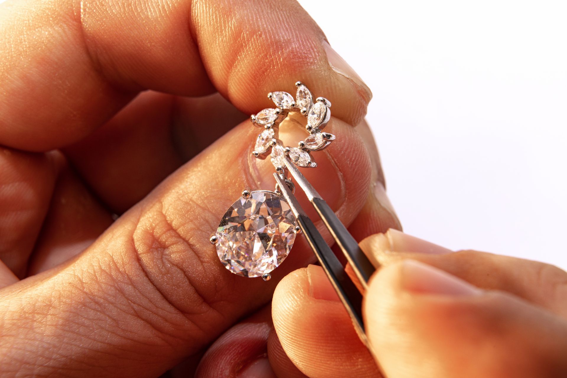 A person is holding a pair of earrings with tweezers