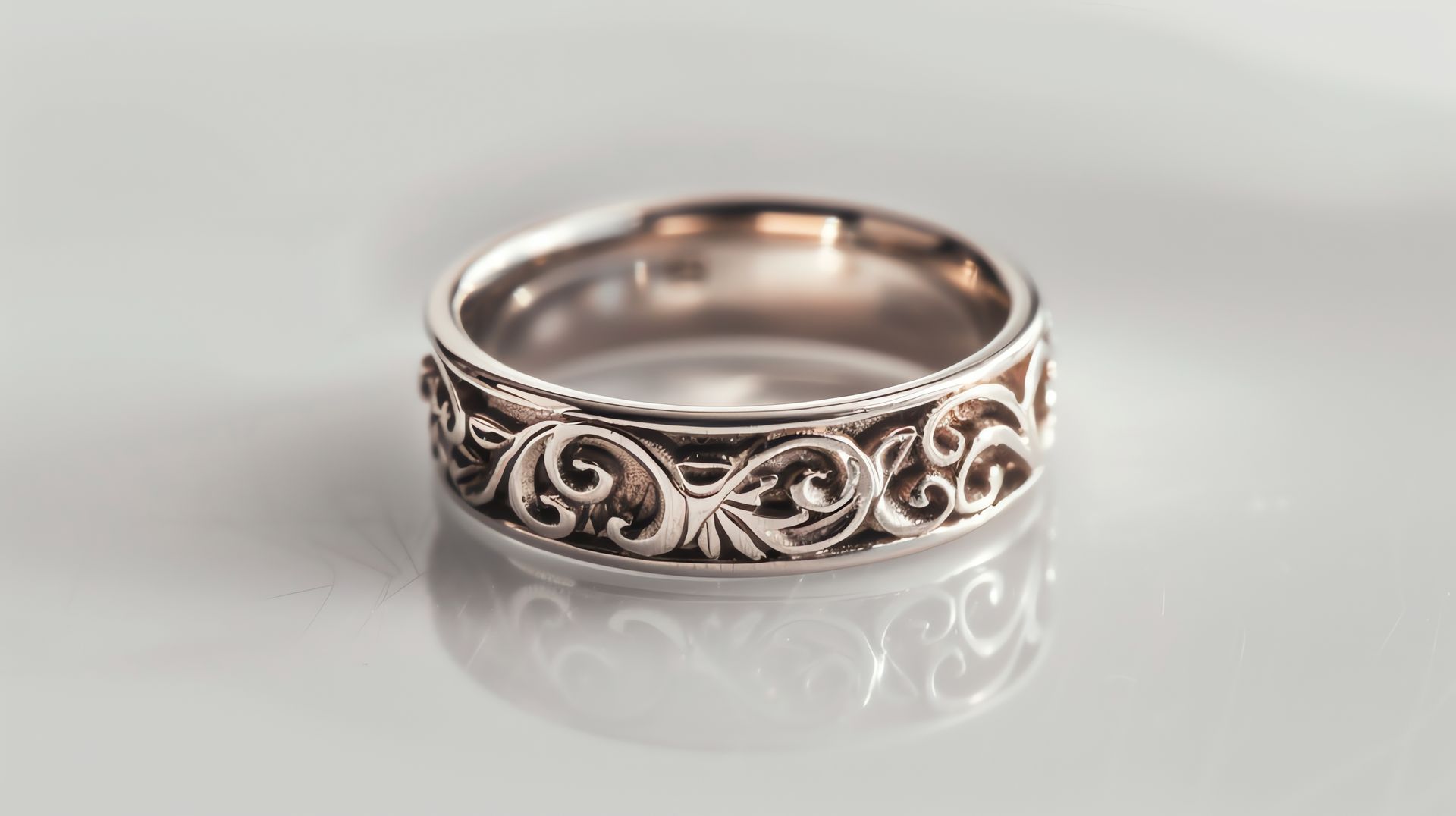 A silver ring with a pattern on it is on a white surface.