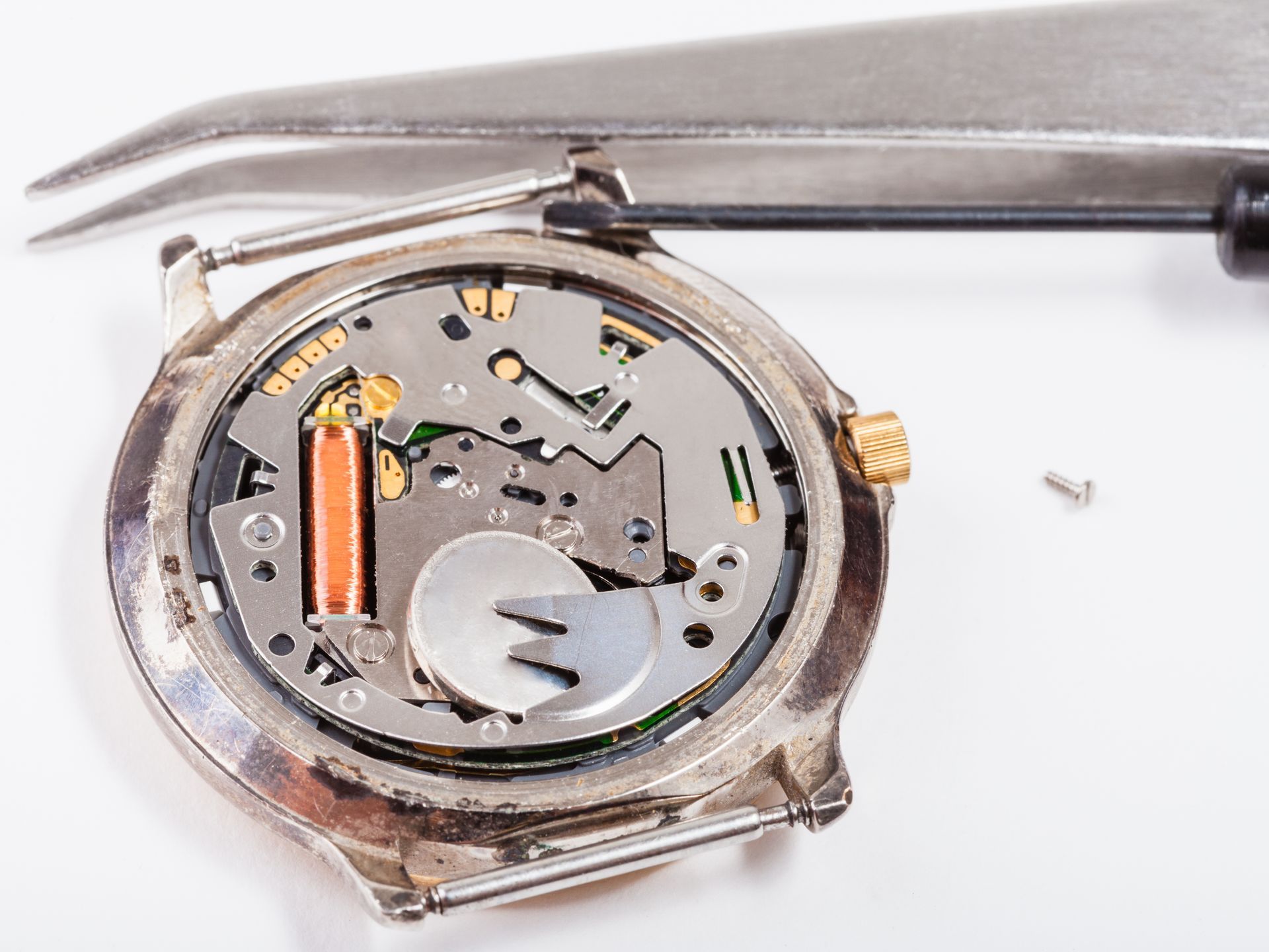 A watch is being repaired with a pair of tweezers