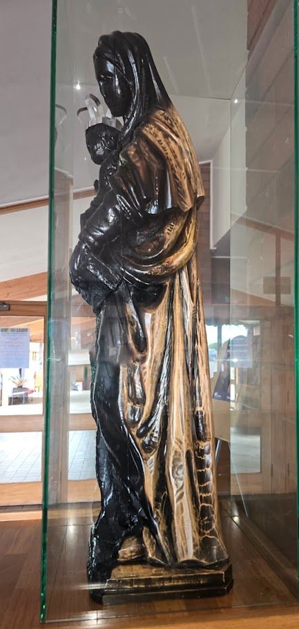 Restored sandalwood statue in protective glass display.