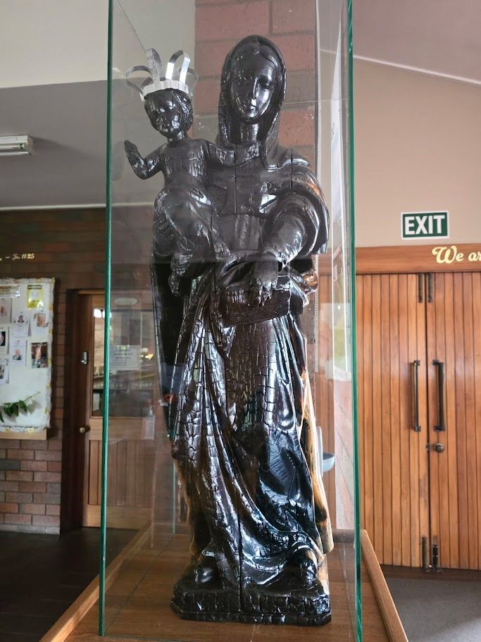 Restored sandalwood statue in protective glass display.