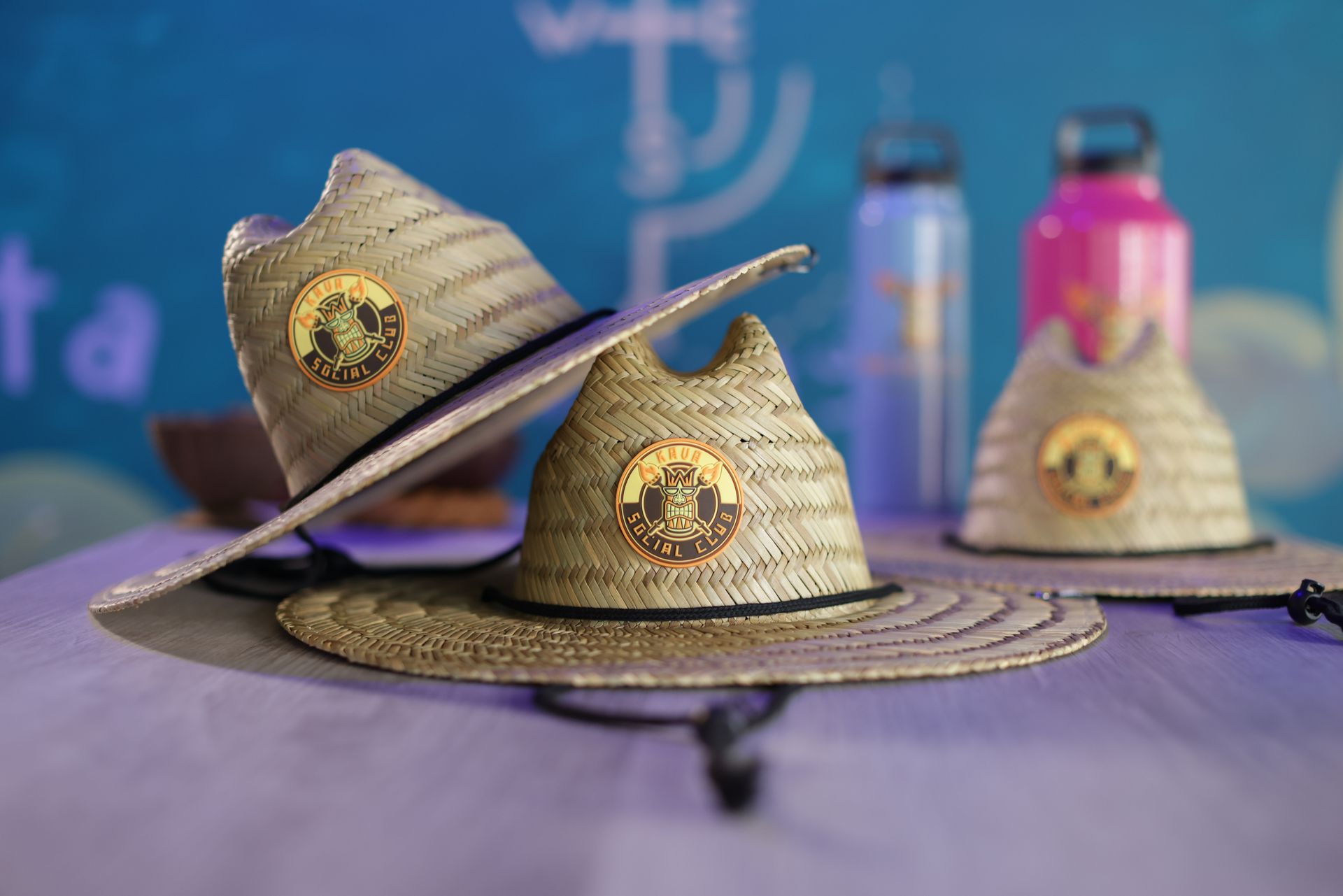 Three straw hats are sitting on a table next to water bottles.