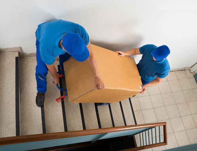 team moving a box up a flight of stairs
