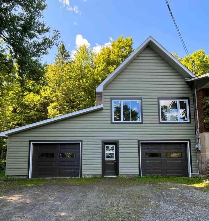 Une maison avec deux portes de garage et deux fenêtres