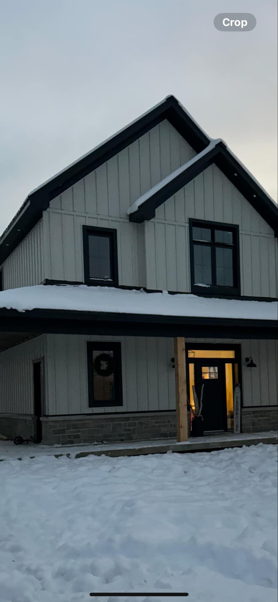 Une maison blanche avec des garnitures noires est recouverte de neige.