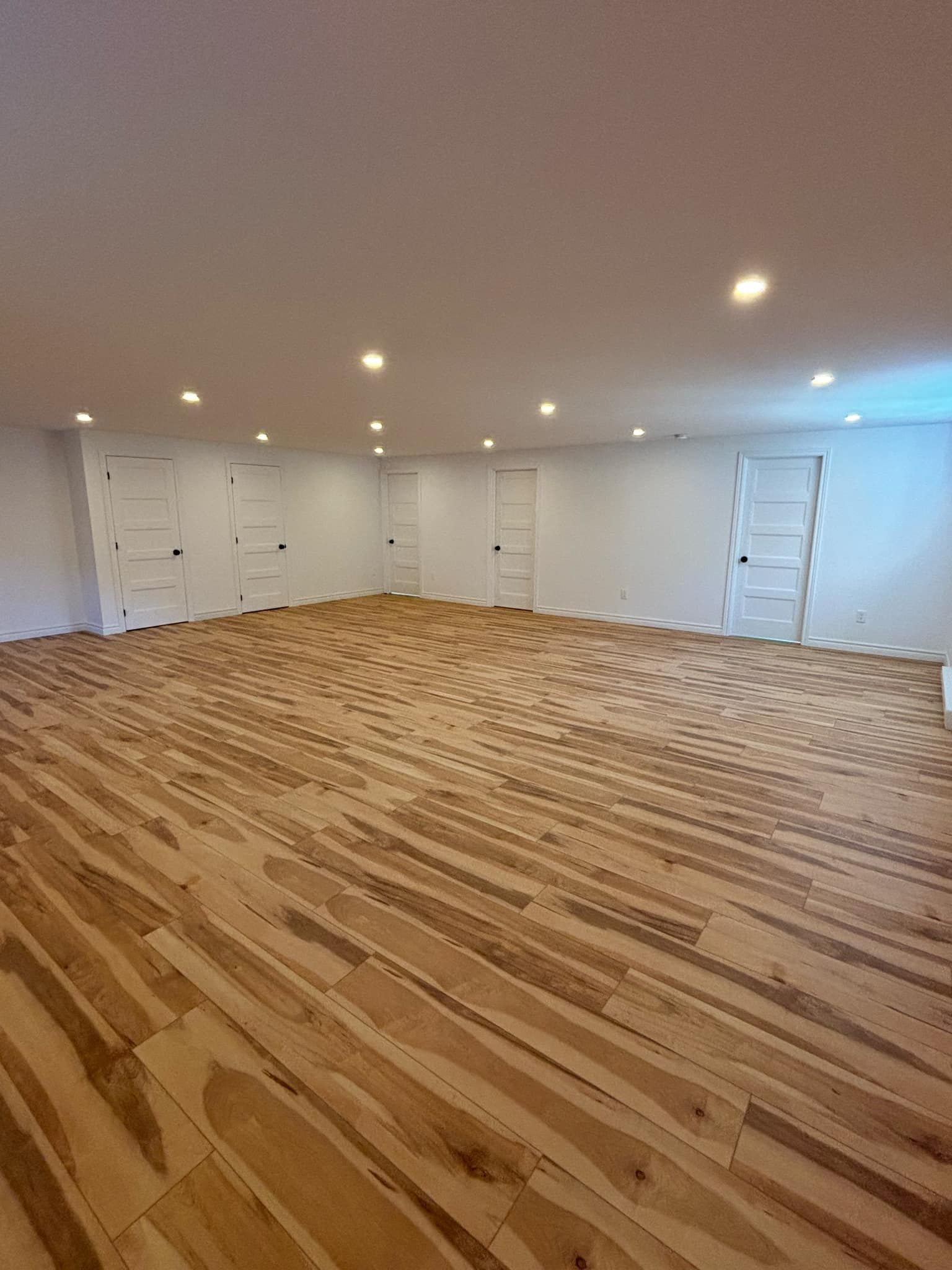 Une grande pièce vide avec du parquet et des murs blancs.