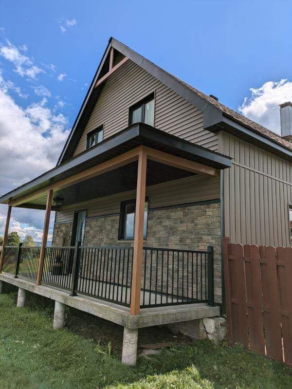 Une maison avec un porche et une clôture devant.