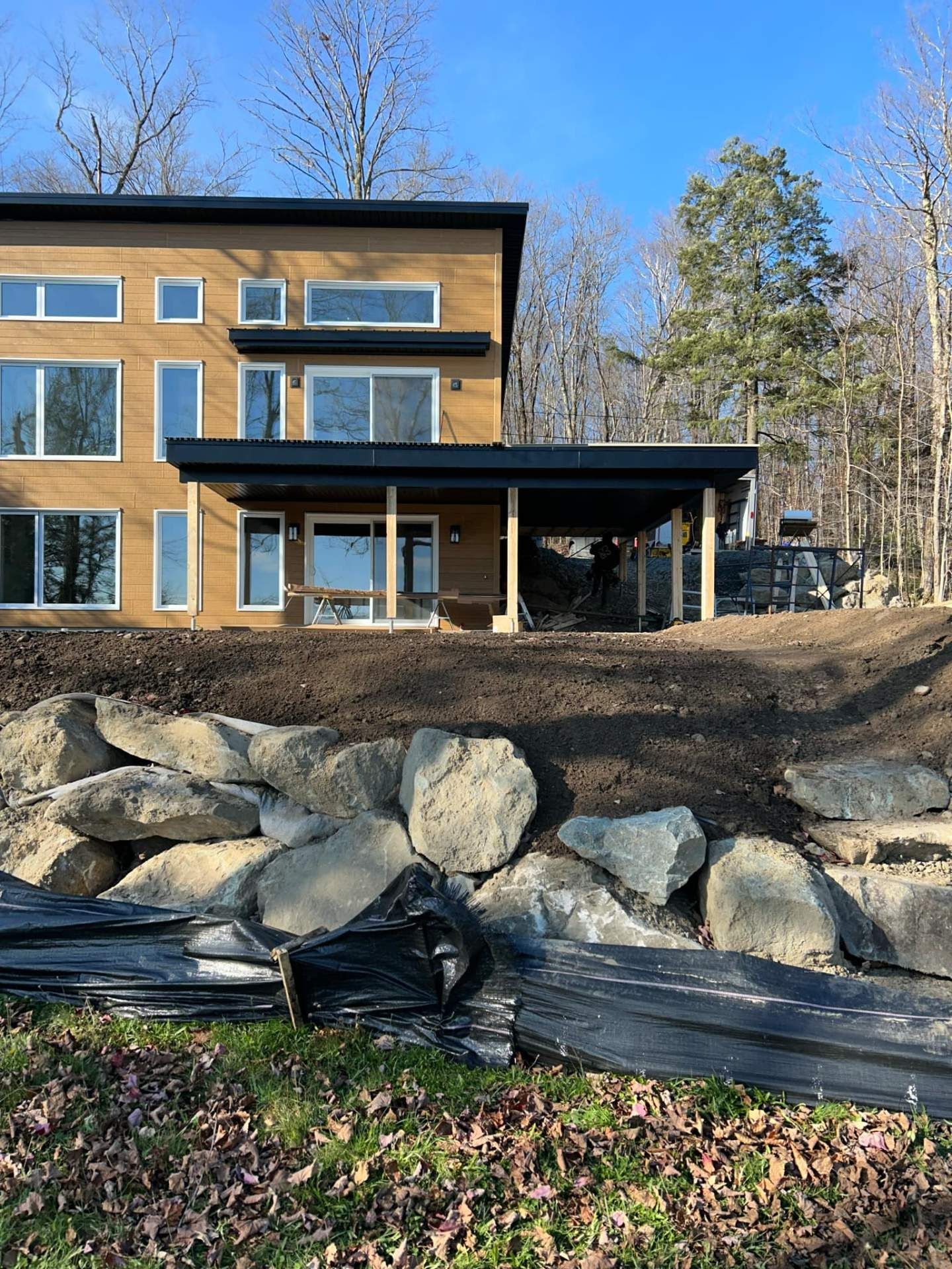 Une grande maison est située au sommet d'une colline à côté d'un mur de pierre.