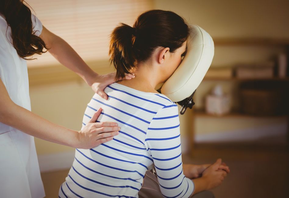 A woman is getting a massage from a women with a massager on face — Relaxing Group Massage on the Gold Coast, QLD