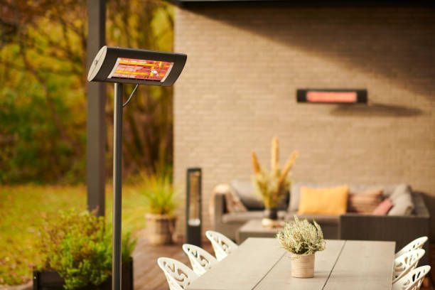 Outdoor patio with heater on a pole, table, chairs, and sofa.  Red-orange infrared heaters.