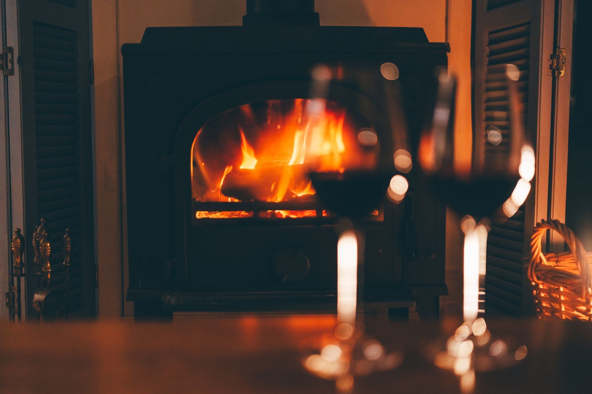 Fireplace with flames and two glasses of red wine.
