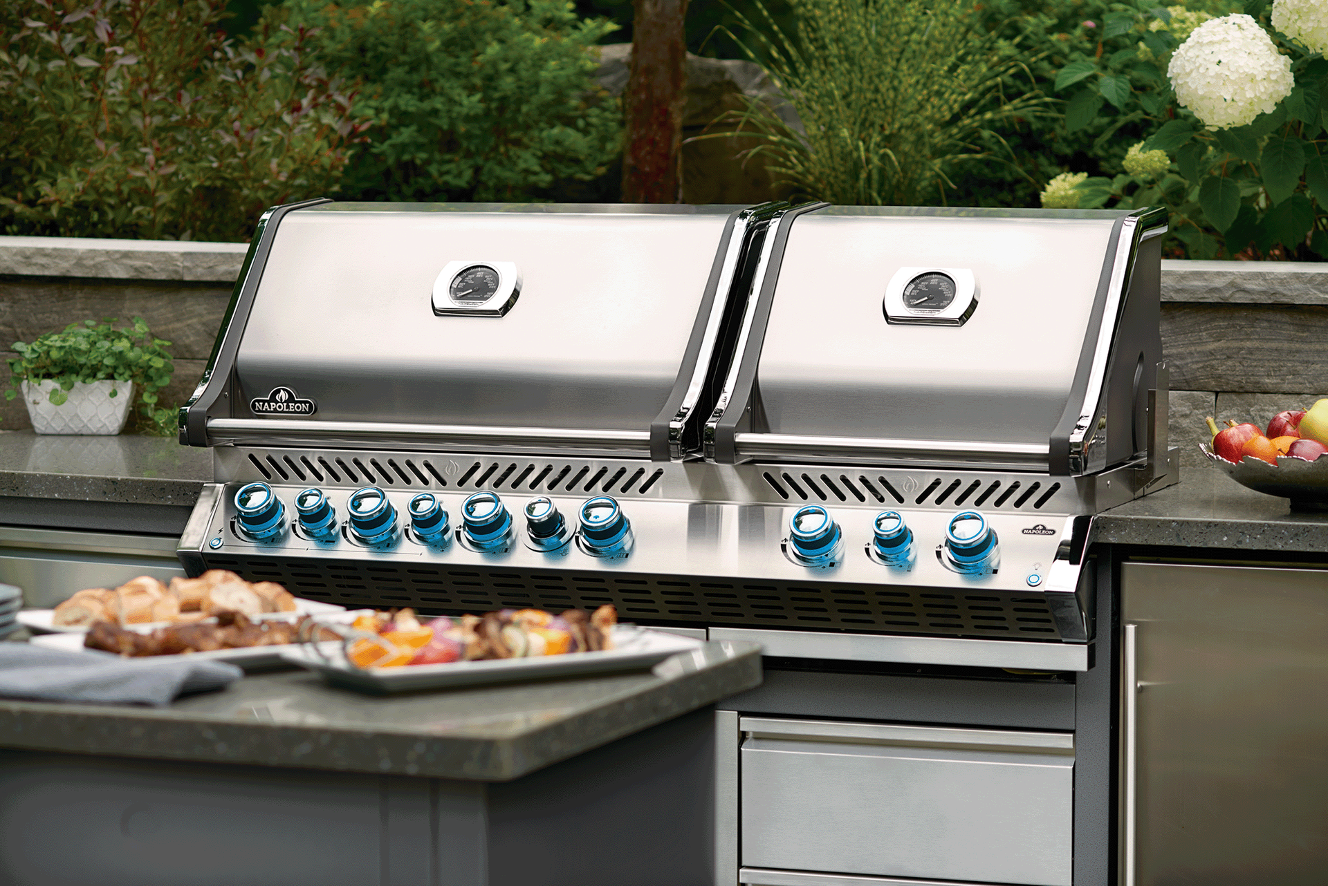 Stainless steel outdoor grill with two lids and blue control knobs. Stainless steel outdoor grill with two lids and blue control knobs.