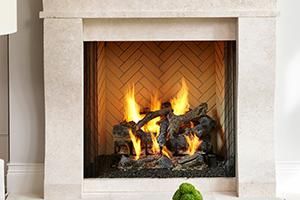 Fireplace with burning logs, light-colored stone surround, and herringbone brick firebox.