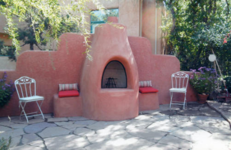 An outdoor fireplace has a pair of chairs in a lounge area.