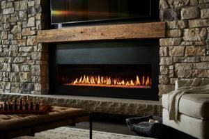 Fireplace with stone surround, lit flames, wooden mantel, and TV above.