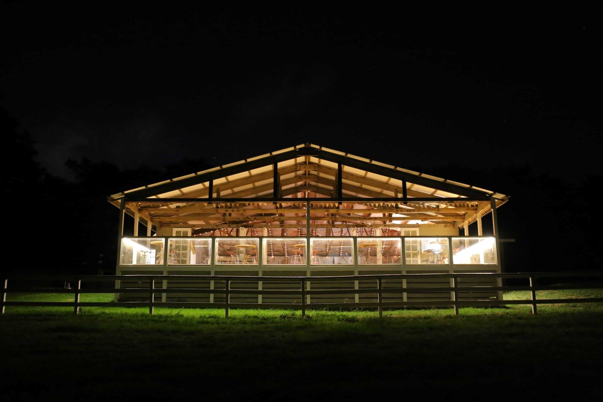 A large building is lit up at night with a fence in front of it.