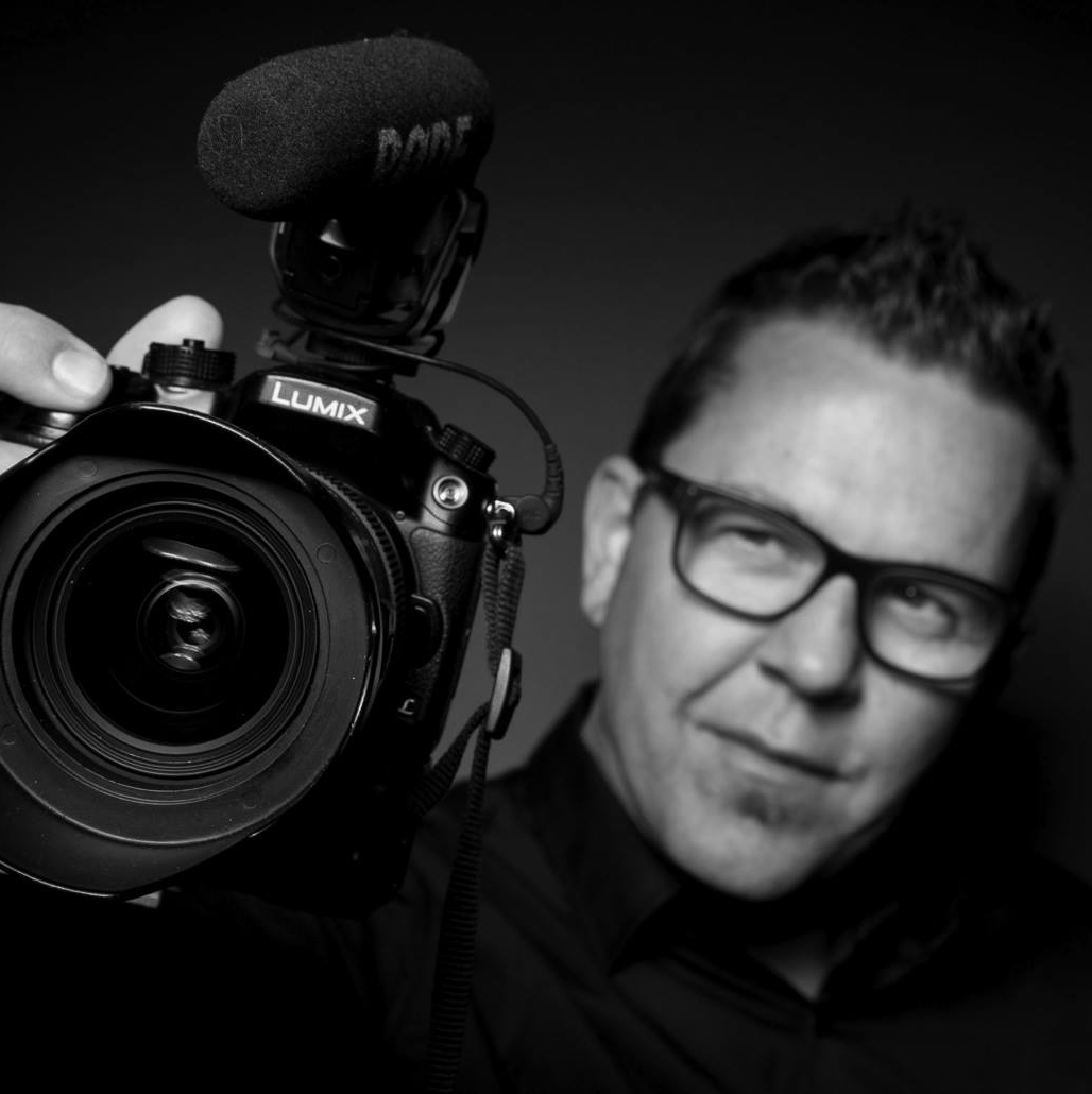 A man is holding a camera that says lumix on it