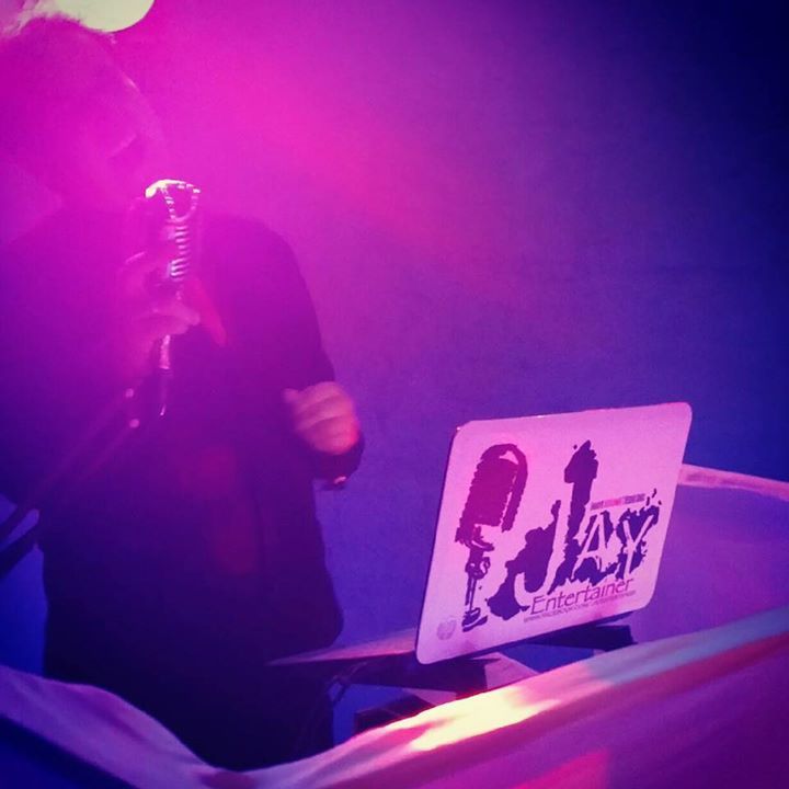 A man singing into a microphone in front of a sign that says play