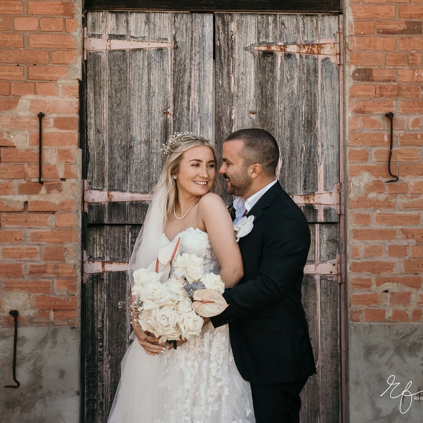 A bride and groom are posing for a picture in front of a wooden door.