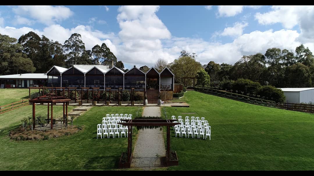 A row of white chairs are lined up in a grassy field in front of a building.
