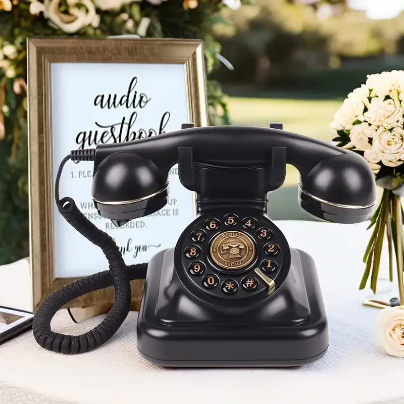 A black telephone is sitting on a table next to a sign that says audio guestbook