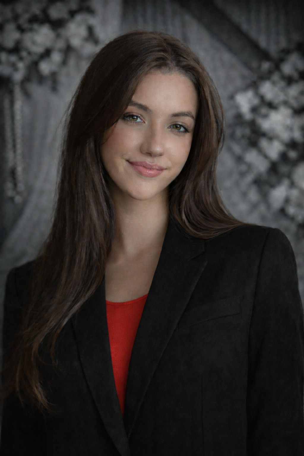 Woman with long brown hair, smiling, wearing a black top against a blurred yellow background.