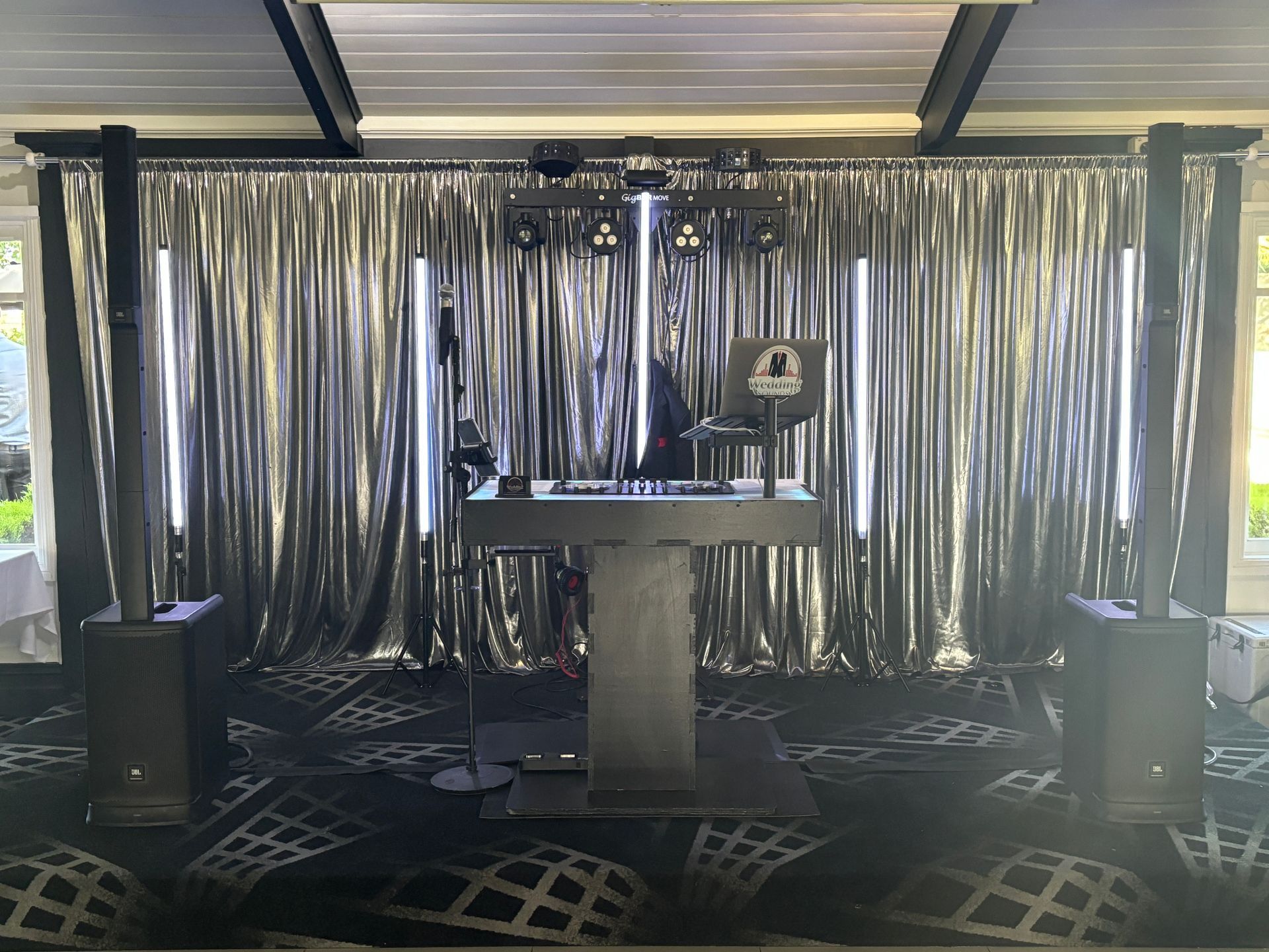A dj booth is sitting in front of a silver curtain in a room.