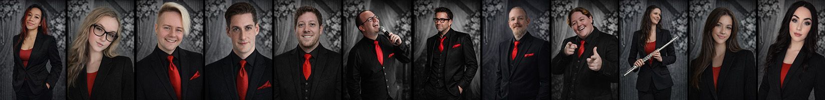 Group of people in dark clothing, possibly band members. Several smiling, one with a saxophone.