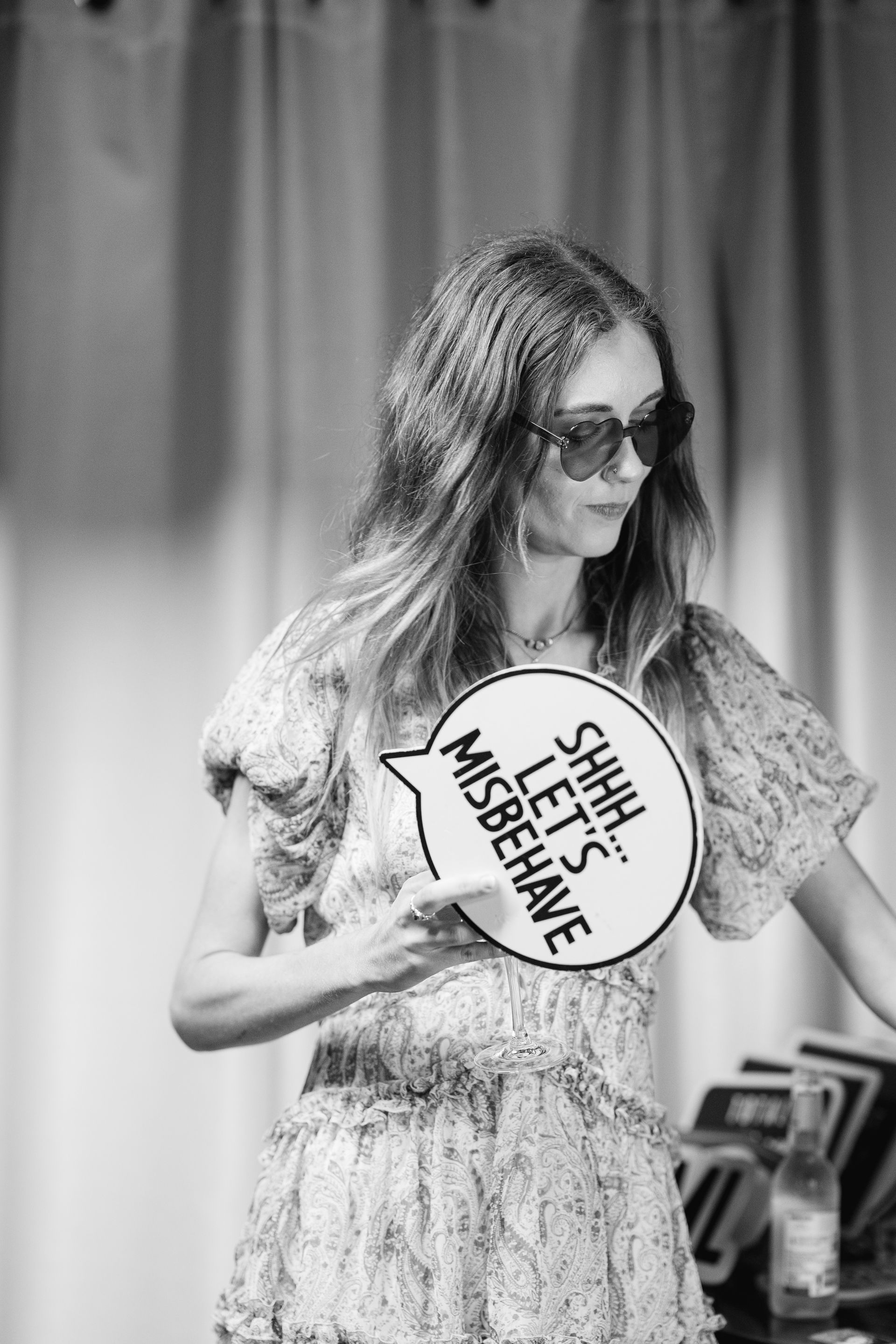 Woman wearing sunglasses holding a speech bubble that says 