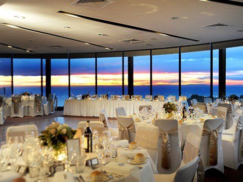 A large room filled with tables and chairs with a view of the ocean